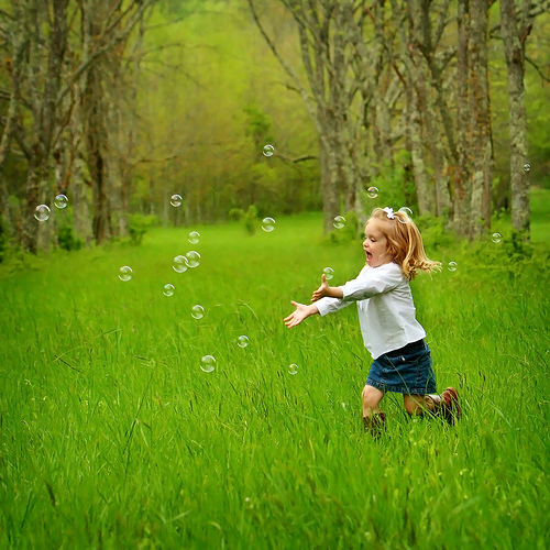Bambina insegue bolle di sapone