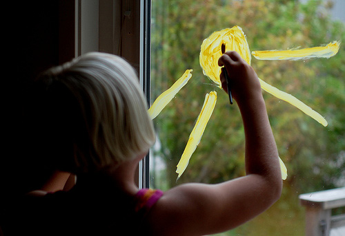 Bimba dipinge sole sul vetro