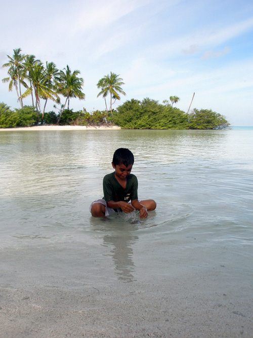 Bambino seduto in riva al mare